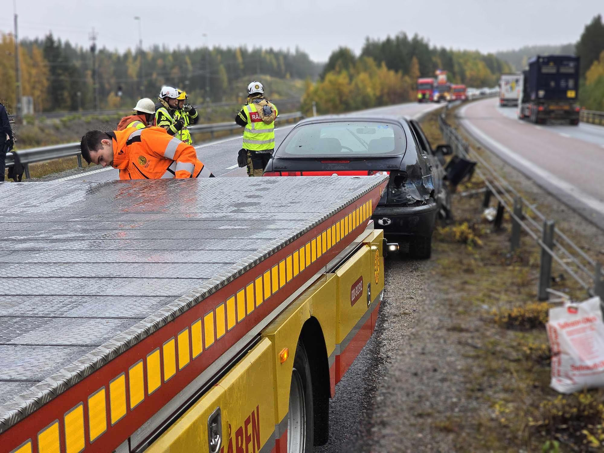 Bärgningstekniker lastar en krockad bil på motorvägen med räddningstjänst på plats, akut bärgning